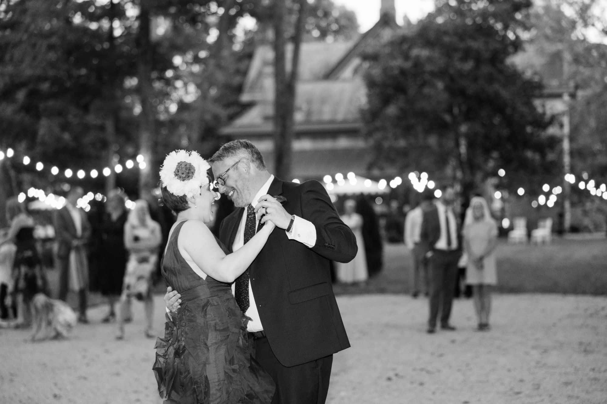A couple sharing their first dance beneath string lights at their wedding